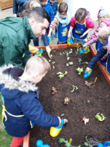 Kindergartenkinder gießen Pflanzen im neuen Hochbeet
